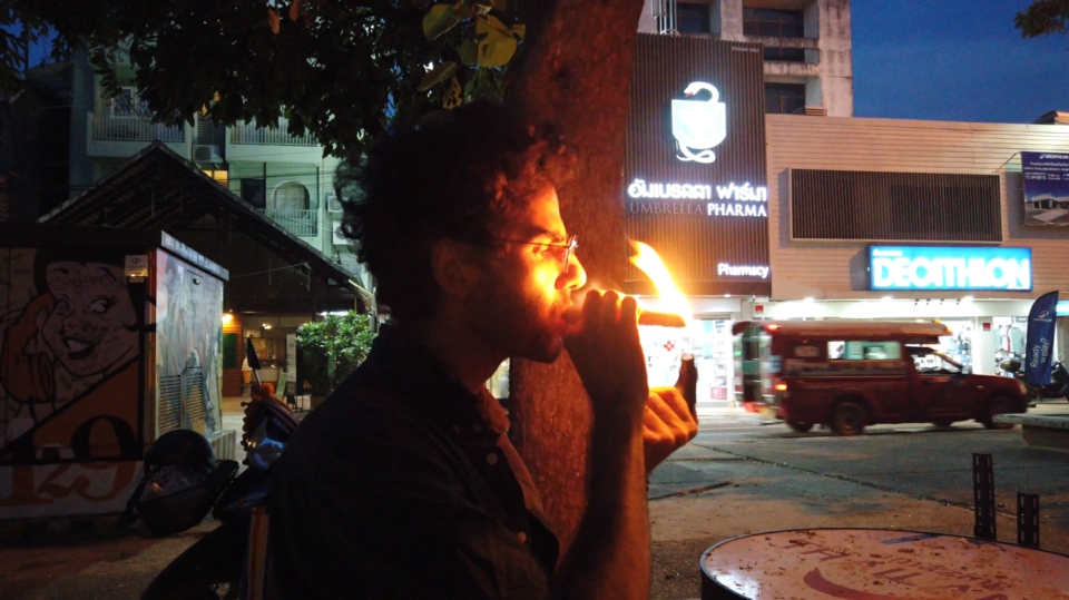 the artist lights a cigar, a strong flame illuminatingn his face.
