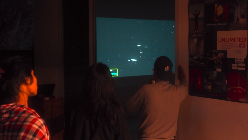 audience members look on from outside the venue. Inside, a viewport of space can be seen. Stars and planet systems are replaced by three-dimensional words.